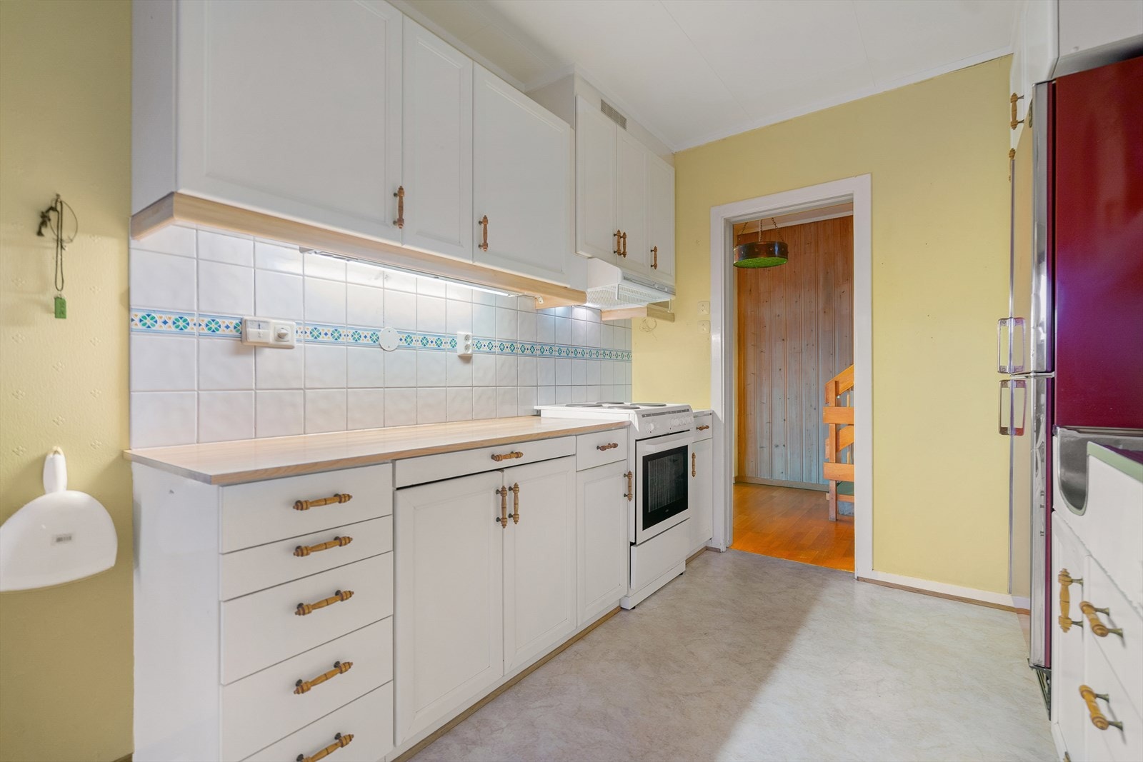 Kjøkkeninnredning har lysmalte profilerte og slette fronter. Benkeplate av laminat og flislagt over benk. Galleribilde