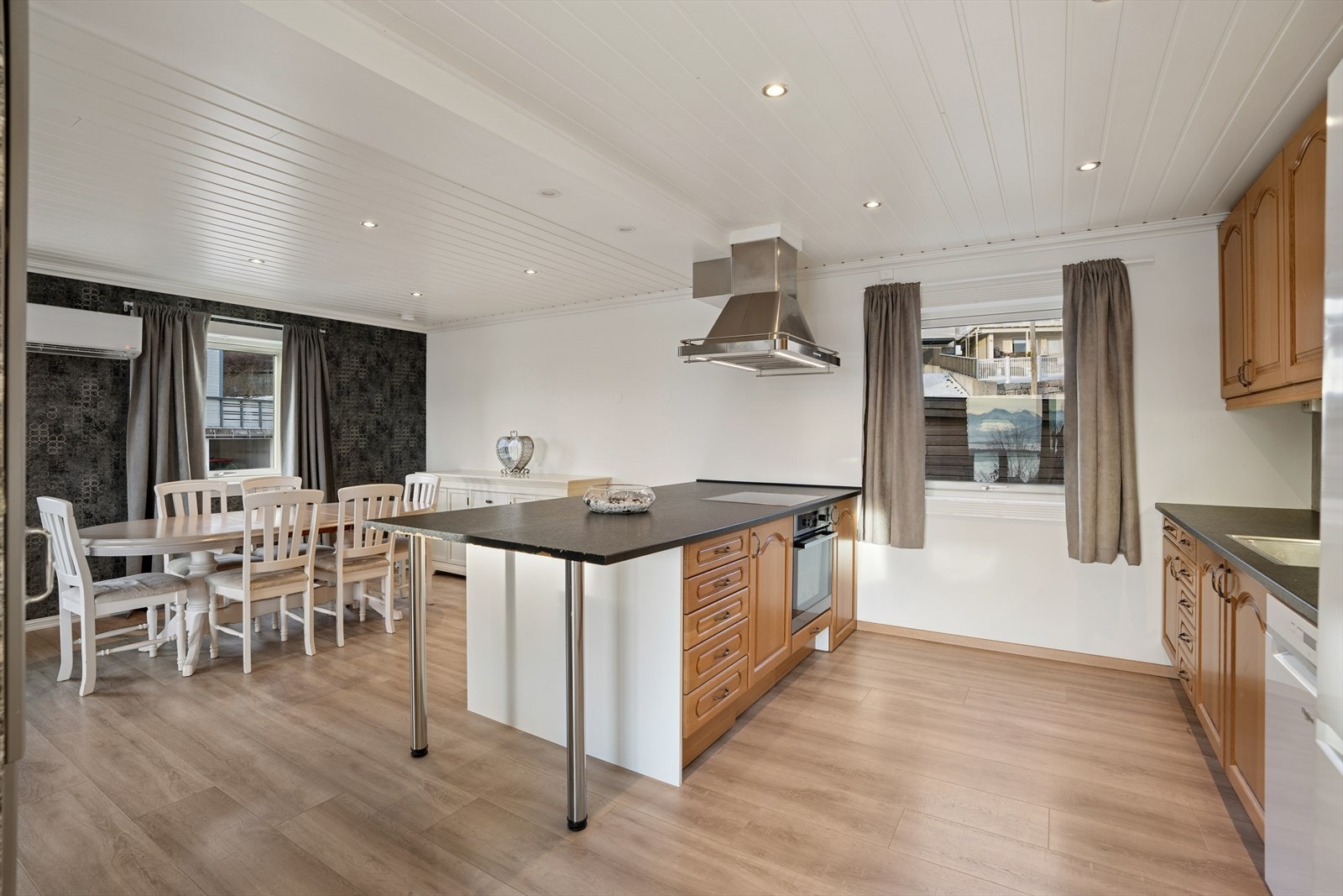 Innredningen består av skap med profilerte fronter og en laminat benkeplate, supplert av en praktisk kjøkkenøy som gir ekstra arbeidsflate og gode oppbevaringsmuligheter. Galleribilde