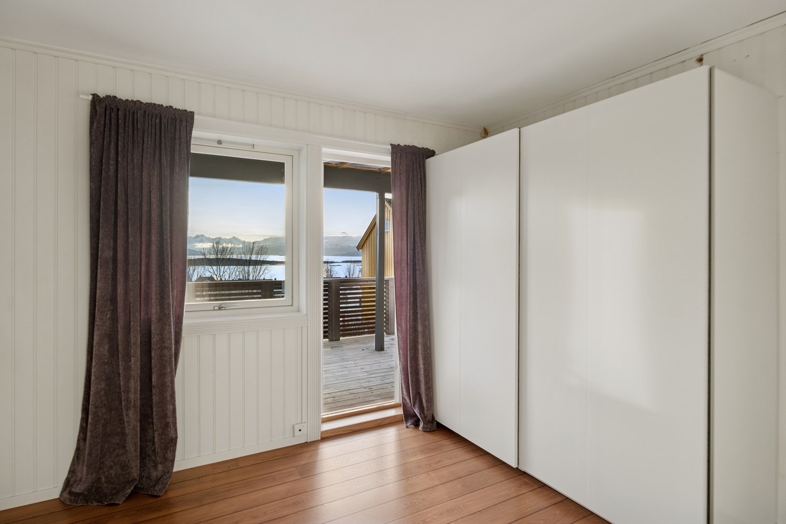 Ett av soverommene fungerer som hovedsoverom med stort garderobeskap med skyvedører. Herfra er det direkte utgang til en terrasse med nydelig fjordutsikt - en privat og rolig uteplass som gir rommet det lille ekstra. Galleribilde