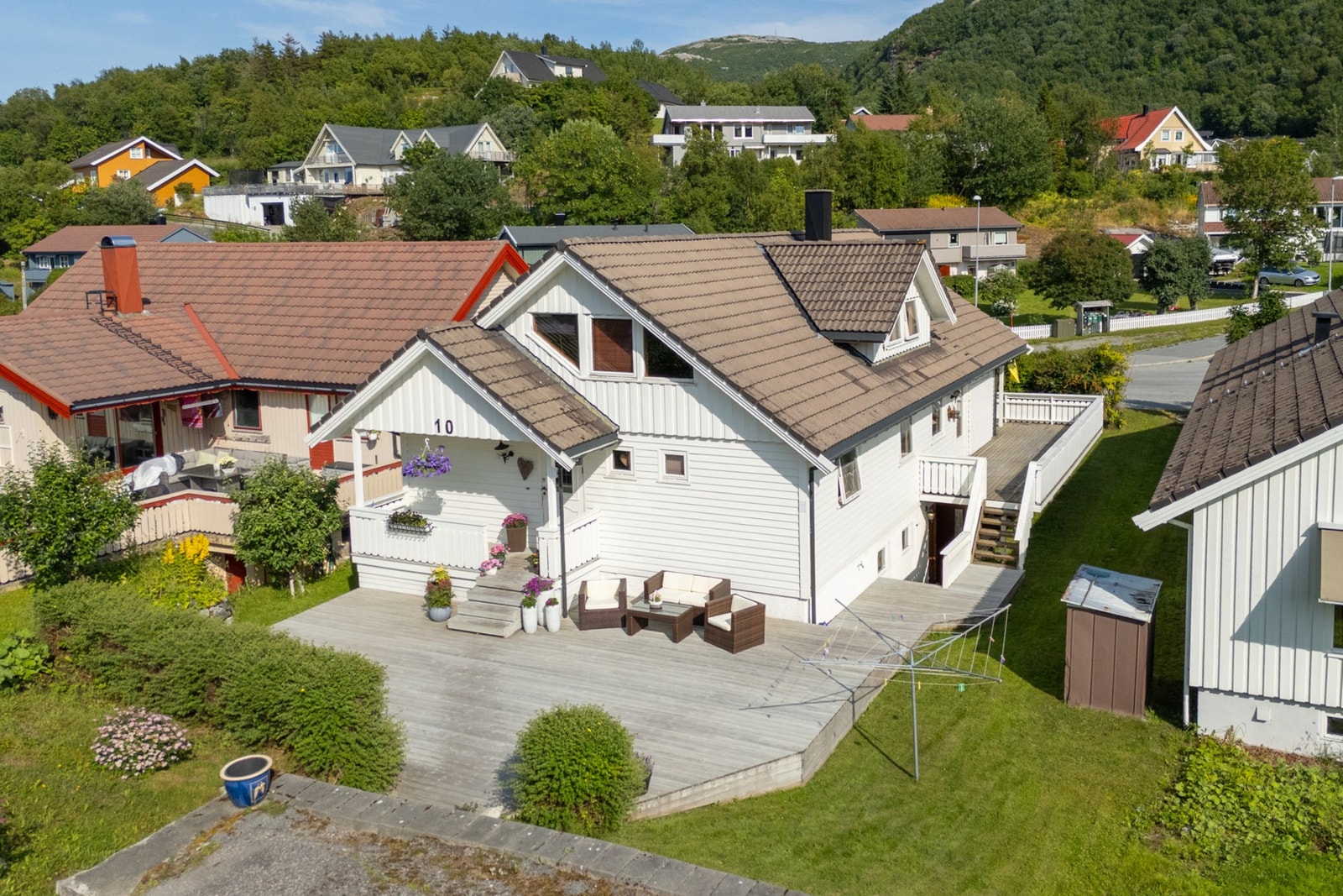 Pent opparbeidet uteområde med plen, platting, støttemur og beplantning. Galleribilde