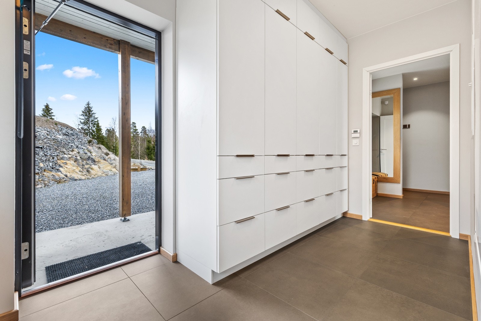 Lys og innbydende grov entre med delikate storformatfliser på gulv med vannbåren gulvvarme og malte slette veggflater, som gir et godt førsteinntrykk av boligen. Det er satt inn stilrene garderobeskap, perfekt til oppbevaring av yttertøy og sko. Galleribilde