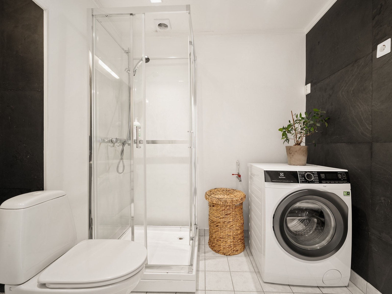 Badet benyttes med dusjkabinett som begrenser vannpåkjenning på overflatene. Veggene er utført med plater og tapet, gulvet har fliser og elektrisk varme. Galleribilde