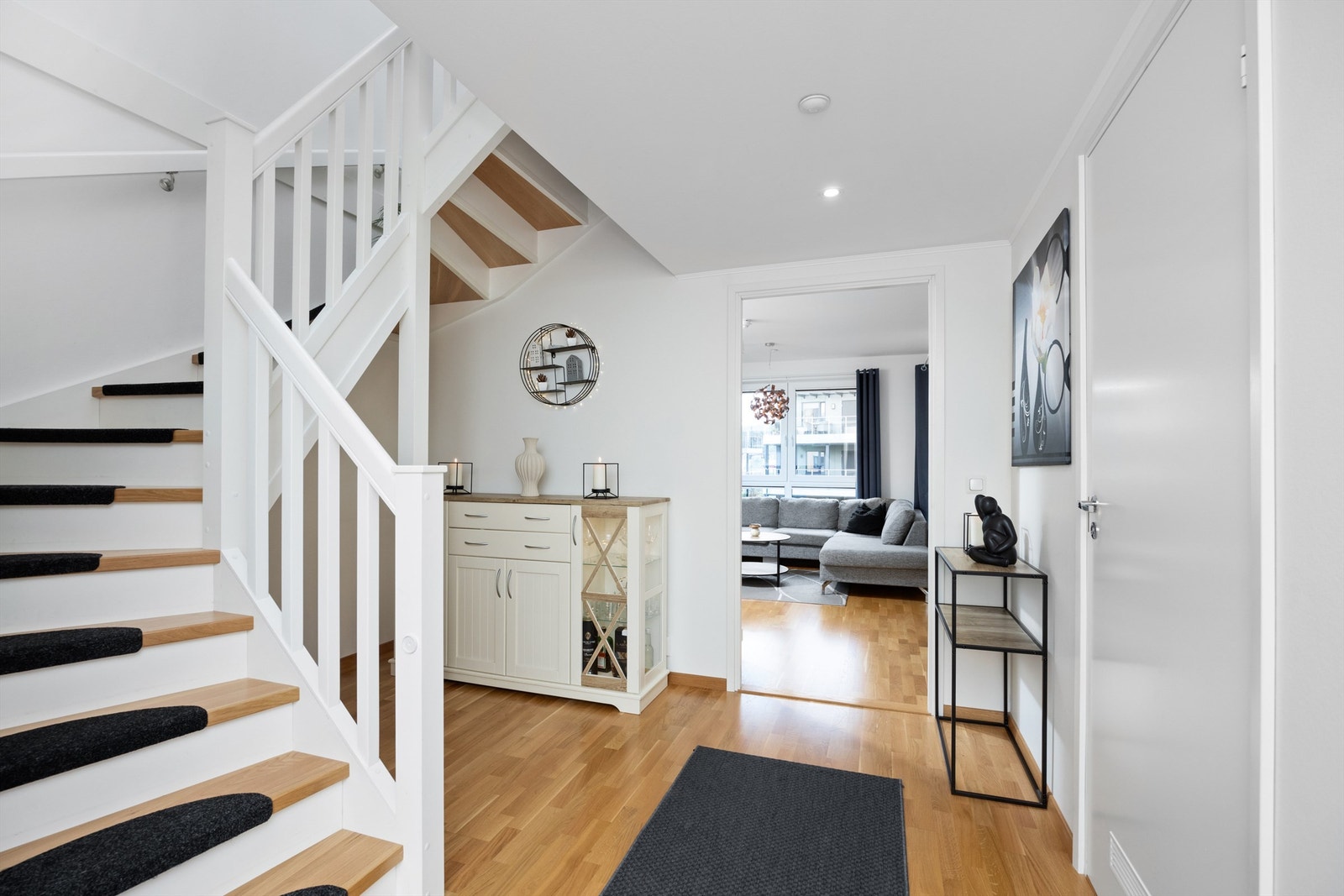 Trivelig og lys hall med trapp opp til leilighetens 2. etasje. Under trappen er det rikelig med plass til diverse oppbevaringsmøblement Galleribilde