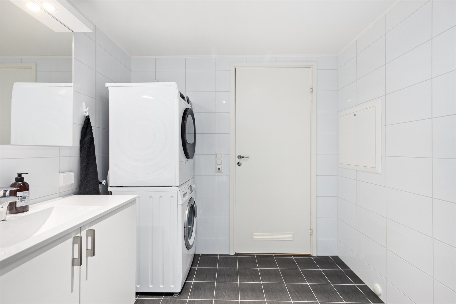 Vegghengt toalett med innbygd sisterne. Opplegg for vaskemaskin. Fliser på gulv og vegger. Varmekabler i gulv og downlights i nedsenket himling Galleribilde