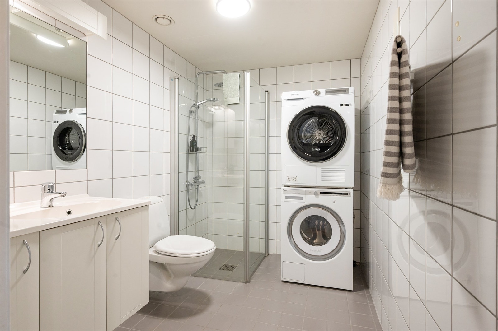 Romslig, flislagt bad med dusjhjørne og opplegg for vaskesøyle. Vannbåren gulvvarme sørger for en behagelig start på dagen. Galleribilde