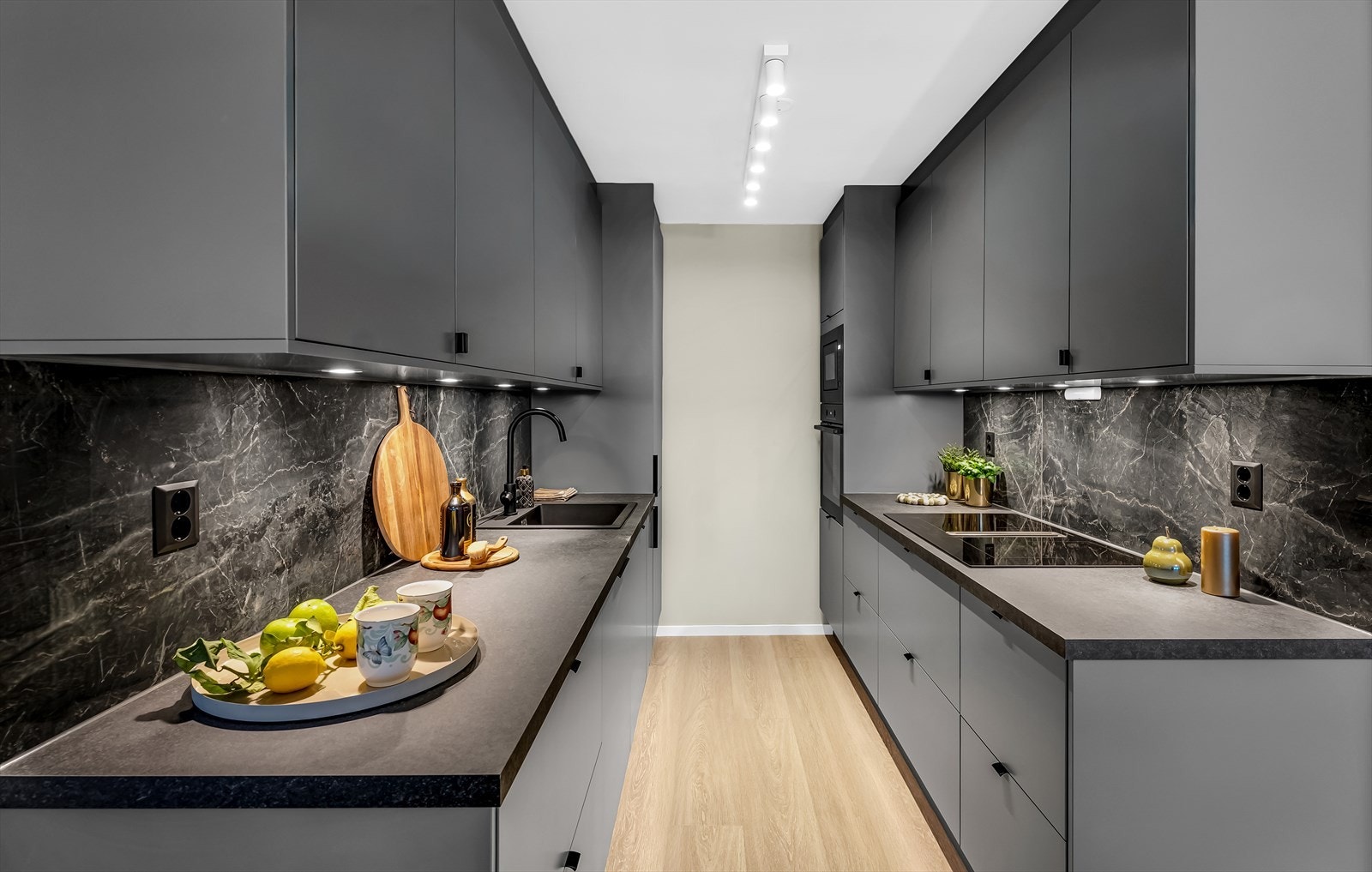 Kjøkkeninnredning med glatte MDF fronter i grånyanser fra Norema. Fliser med marmormønster mellom benkeplate og veggskap tilfører et eksklusivt preg, samtidig som de er praktiske og enkle å vedlikeholde Galleribilde