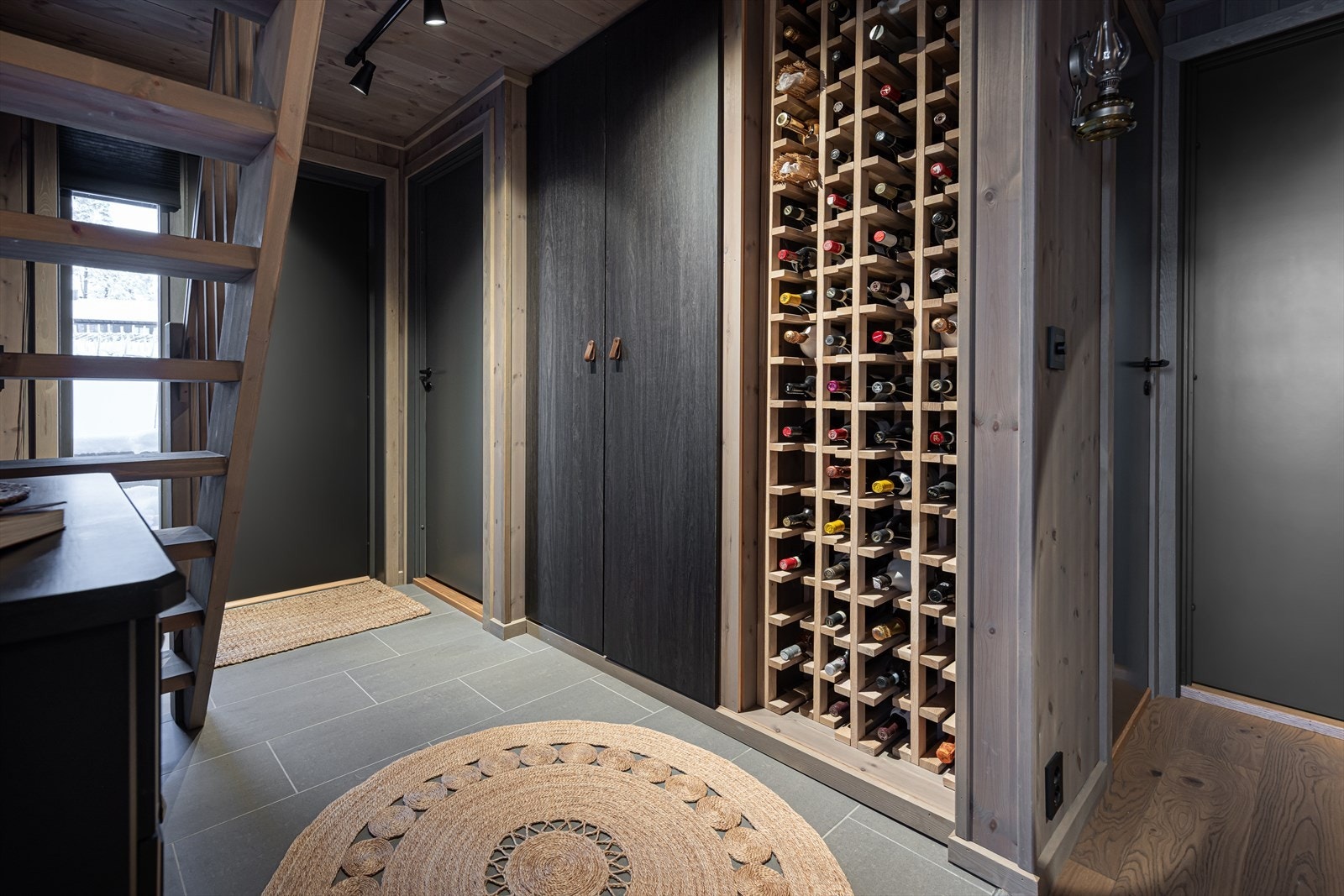 Velkommen inn. Romslig entré med plassbygget skap og vinreoler Galleribilde