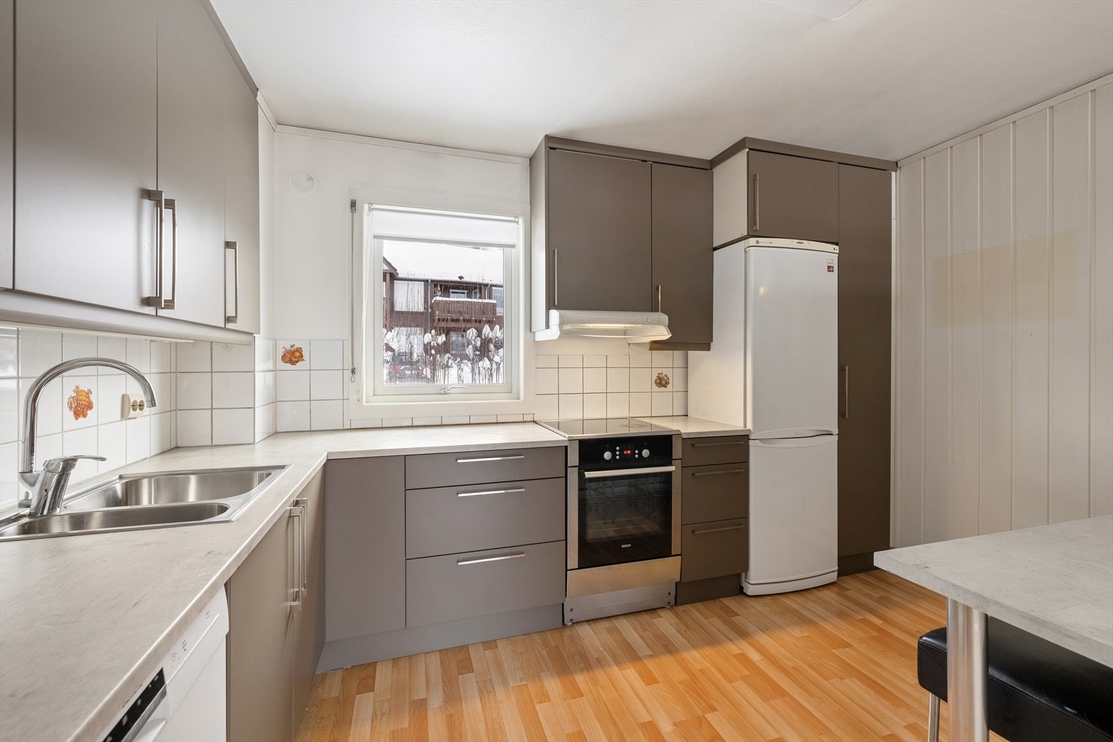 Kjøkkenet er innredet med glatte fronter, laminert benkeplate og flislagt vegg over benkeplaten. Galleribilde