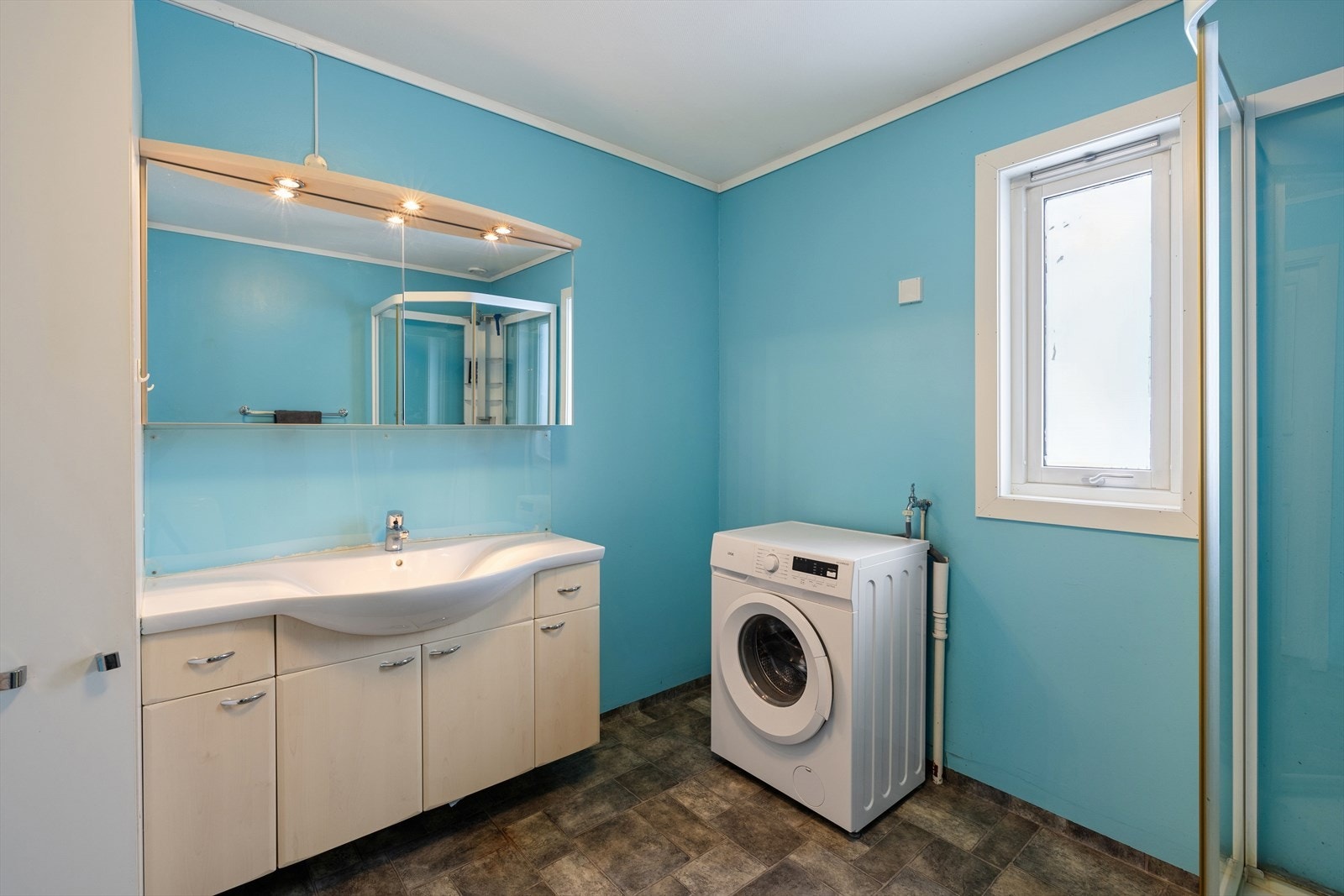 Badet er fra byggeår, og er innredet med servant med underskap, speilskap, dusjkabinett og gulvmontert toalett. Galleribilde