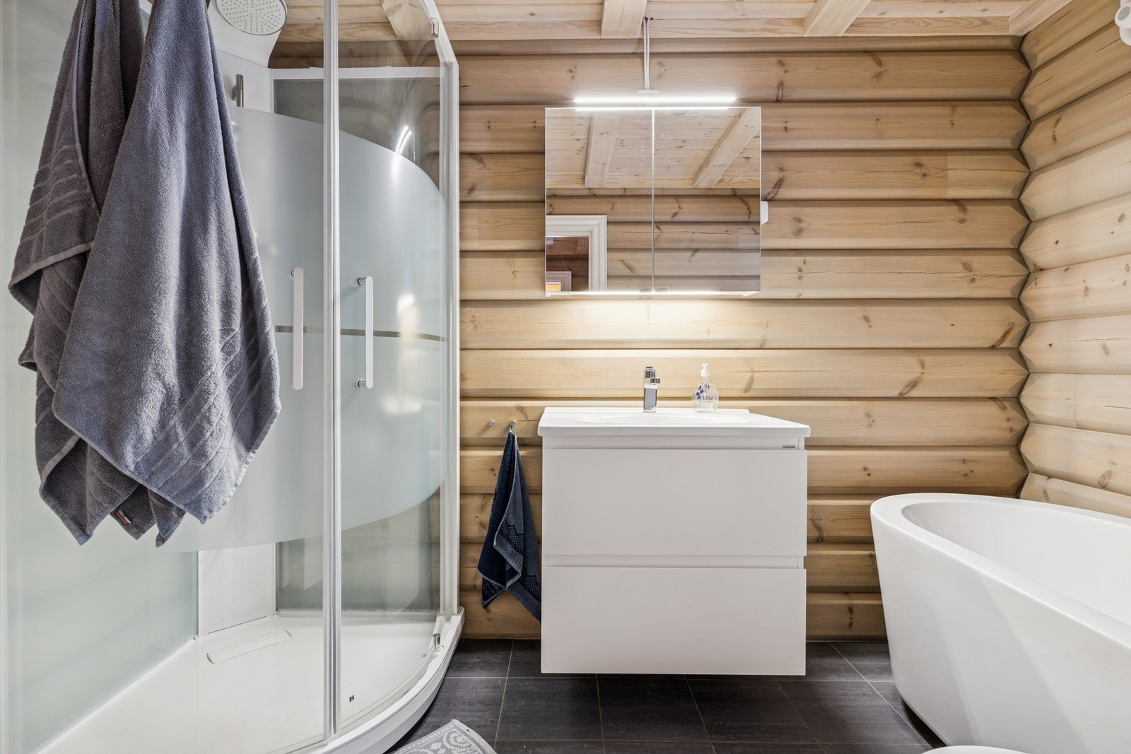 Utstyrt med dusjkabinett, servantskap, servant, veggmontert toalett og badekar. Galleribilde