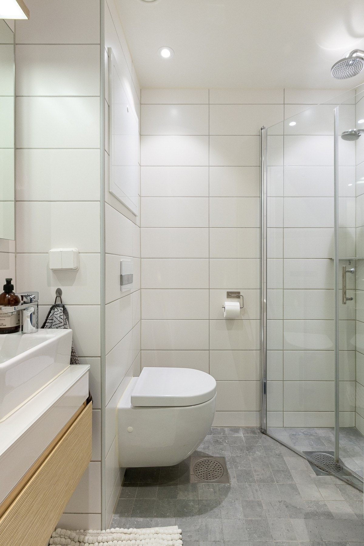 Baderommet er utstyrt med veggmontert toalett, dusj med innfellbare glassdører, servant, speil med lys og uttak til vaskemaskin. Galleribilde