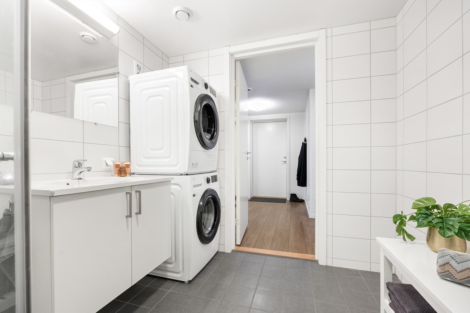 Badet er innredet med gulvstående toalett, dusjhjørne med innfellbare glassdører og servant/vask med belyst speil. Galleribilde