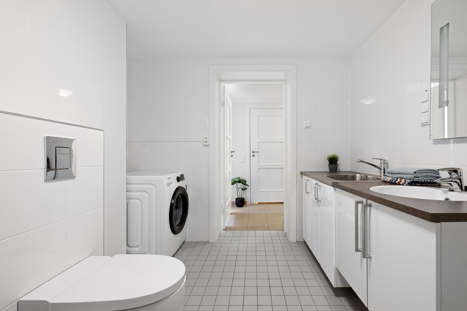 Flis på gulv og vegger.
Praktisk med ubaderomsinnredning, samt utslagsvask og oppbevaring for vaskeprodukter. Galleribilde