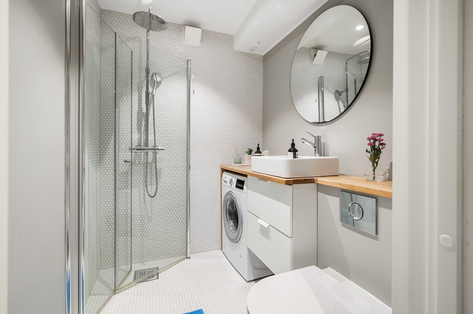 Rommet er innredet med vegghengt toalett, en moderne baderomsinnredning med servant og speil over servanten. Videre har badet dusjhjørne med innfellbare vegger, Galleribilde