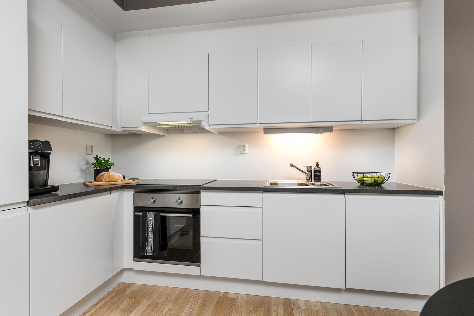 Kjøkkeninnredning med lyse, slette fronter. Rikelig med over- og underskap, samt belysning under overskap. Galleribilde