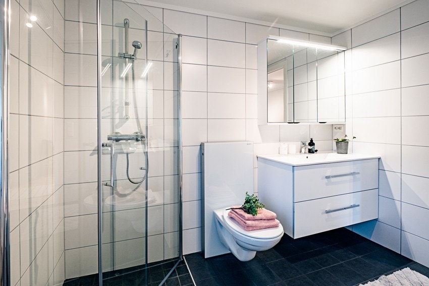 Badet har servant i moderne innredning med skuffer, dusjhjørne og vegghengt toalett Galleribilde