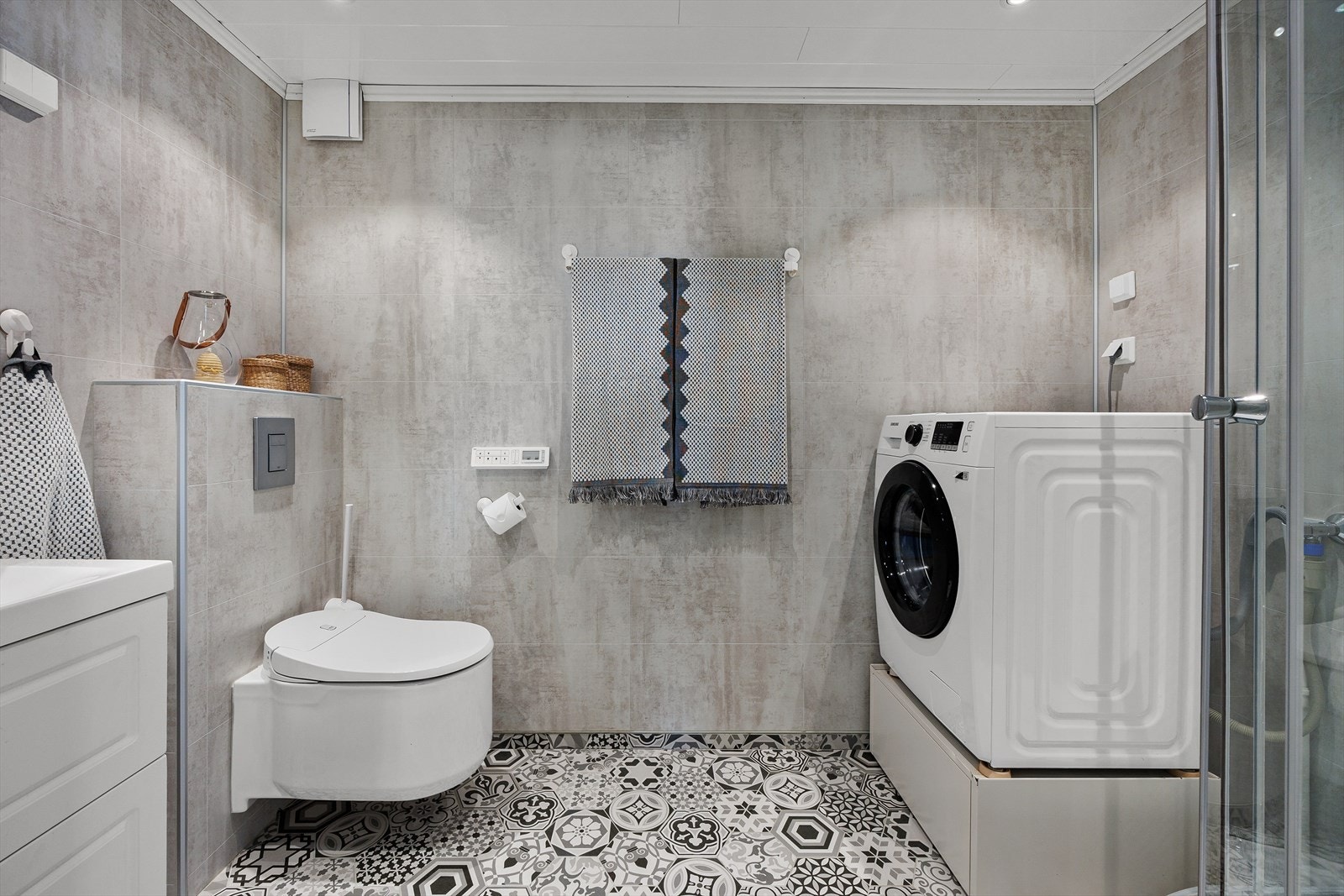 Baderomsinnredning dusjkabinett, servant med underskap, vegghengt toalett og opplegg til vaskemaskin. Galleribilde