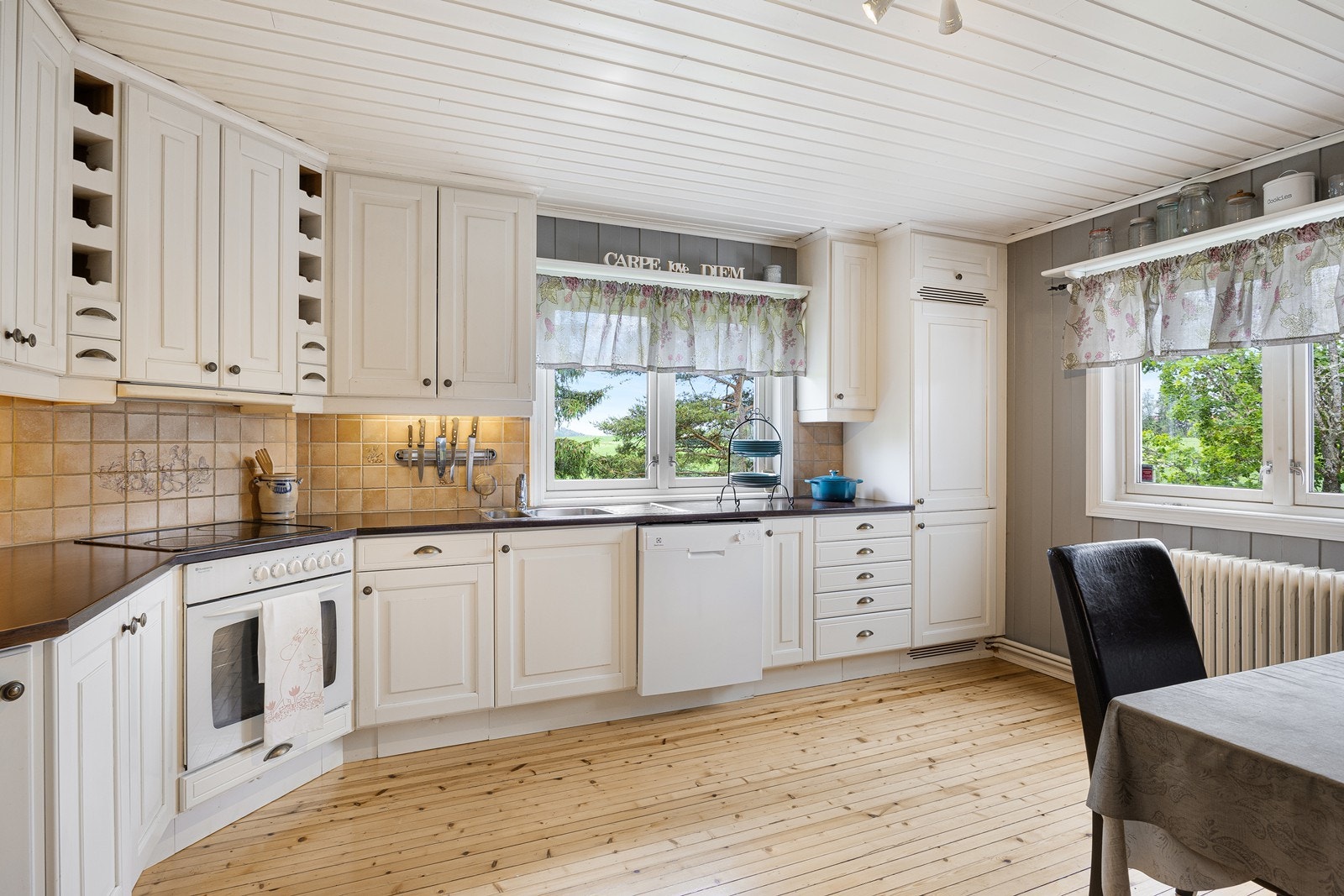 Kjøkkeninnredningen er klassisk, med hvite, profilerte heltrefronter, vinhyller, benkeplate av laminat og dobbel oppvaskkum i stål. Galleribilde