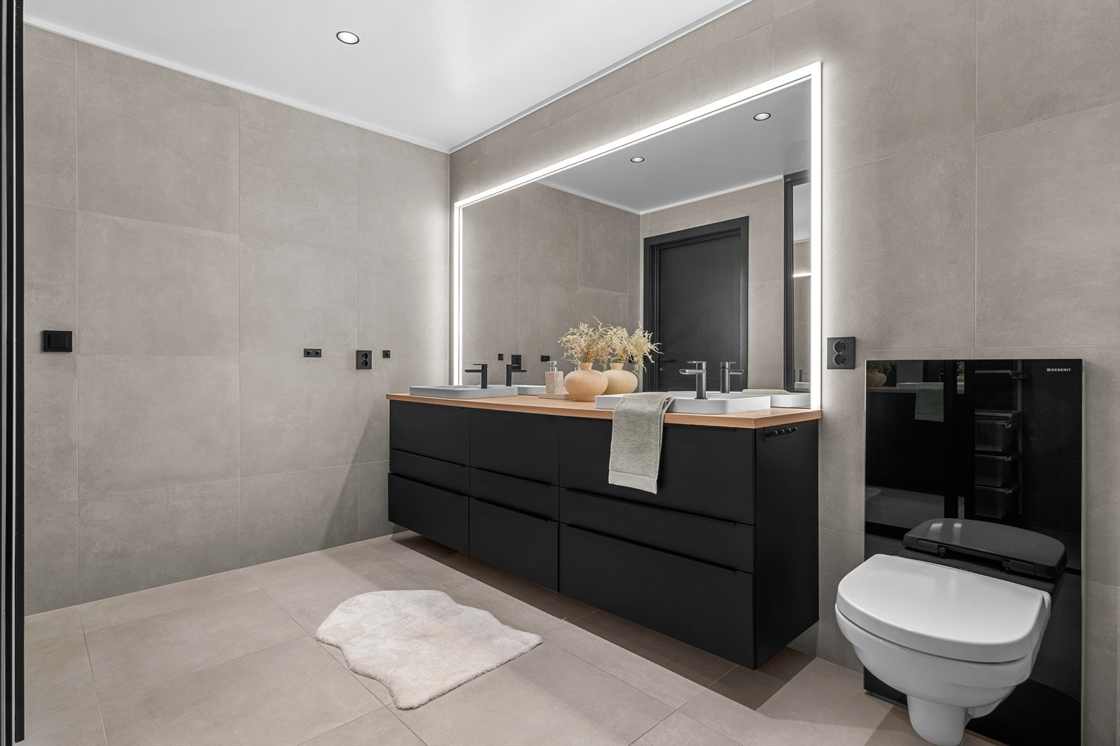 Badet er innredet med en dobbelservant med god oppbevaringsplass i skuffer, samt et praktisk veggmontert speil med integrert lysstripe. Galleribilde