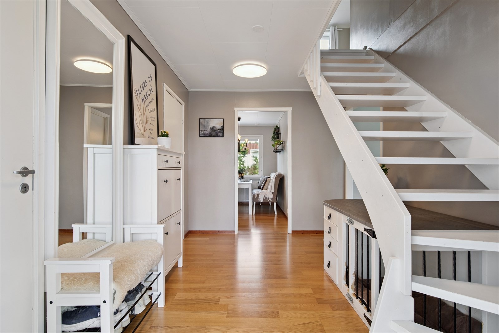 Velkommen inn! Entré med laminatgulv og lyse overflater og en malt, åpen tretrapp som binder etasjene sammen. Galleribilde