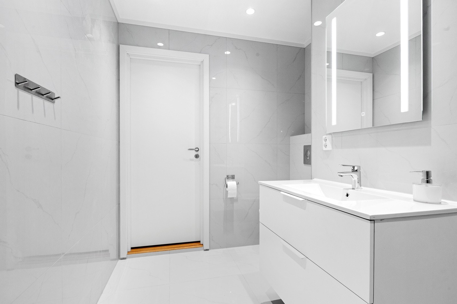 Badet har installert dusjhjørne, toalett, baderomsinnredning med vask og underskap, speil med innfelt lys Galleribilde