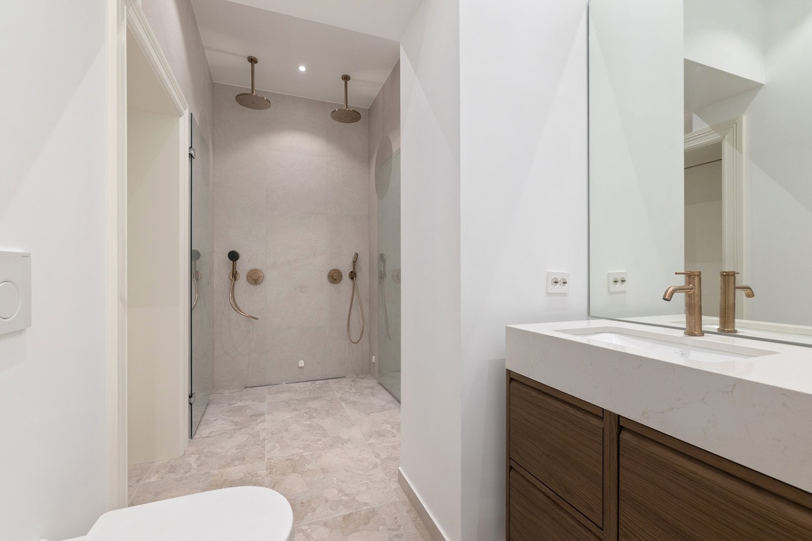 Bad en-suite med inngang fra soverom fra 2025 med vegghengt toalett, dobbel servant med skuffer, dusjnisje med glassdør og to dusjer. Galleribilde