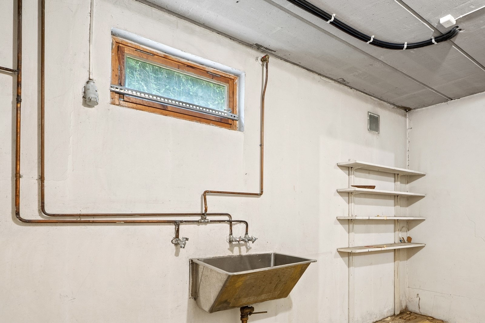 Enkelt vaskerom i underetasjen, innredet med vaskekum og vegghengte hyller. Varmtvannsberederen er også plassert her. Galleribilde