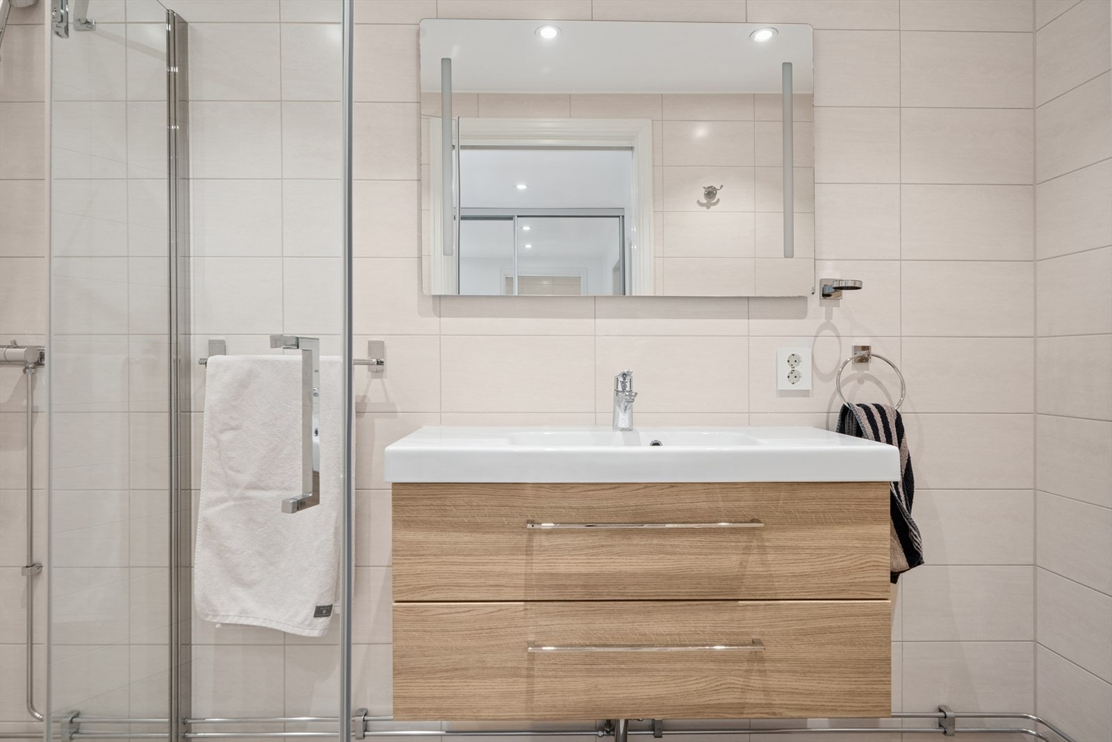 I tilknytning til vaskerommet er et helfliset, stilrent baderom fra 2015 med varmekabler i gulv. Galleribilde