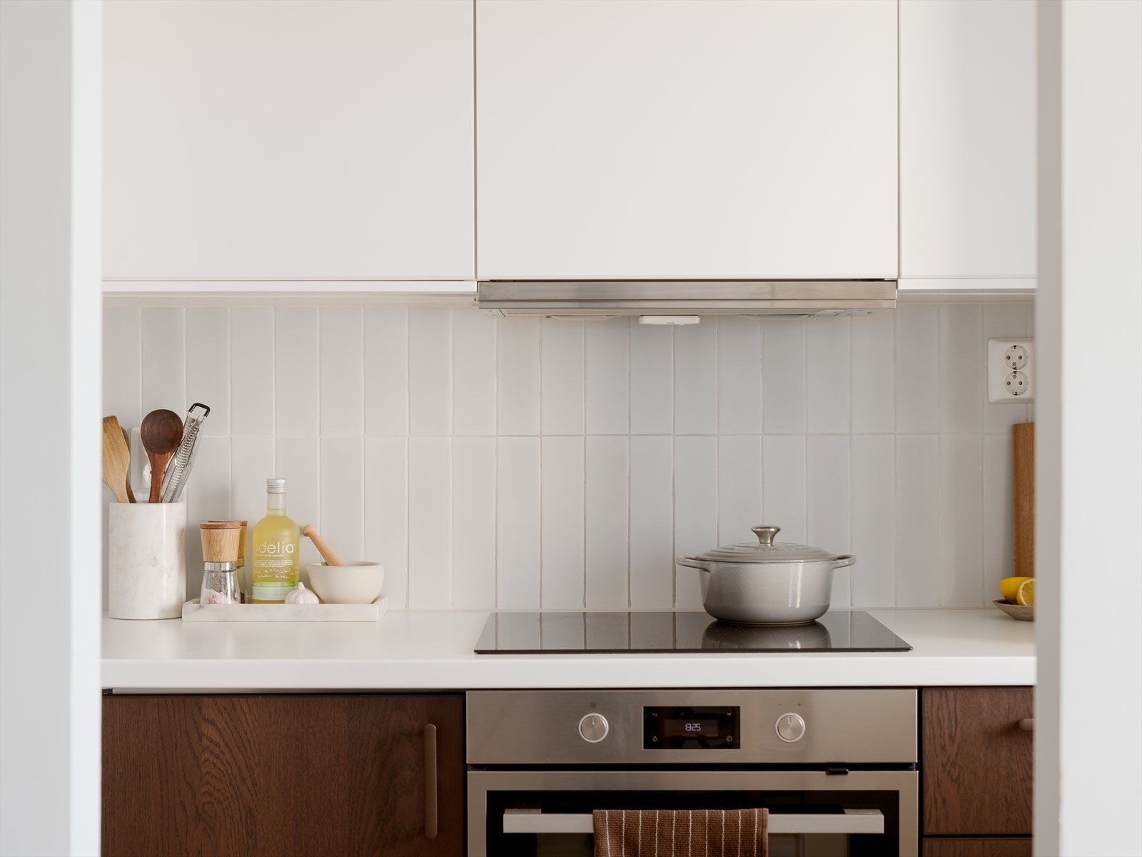 Kjøkkenet har en tidløs og elegant kombinasjon av hvite overskap med push-åpner og laminerte underskap med mørk trestruktur. Galleribilde