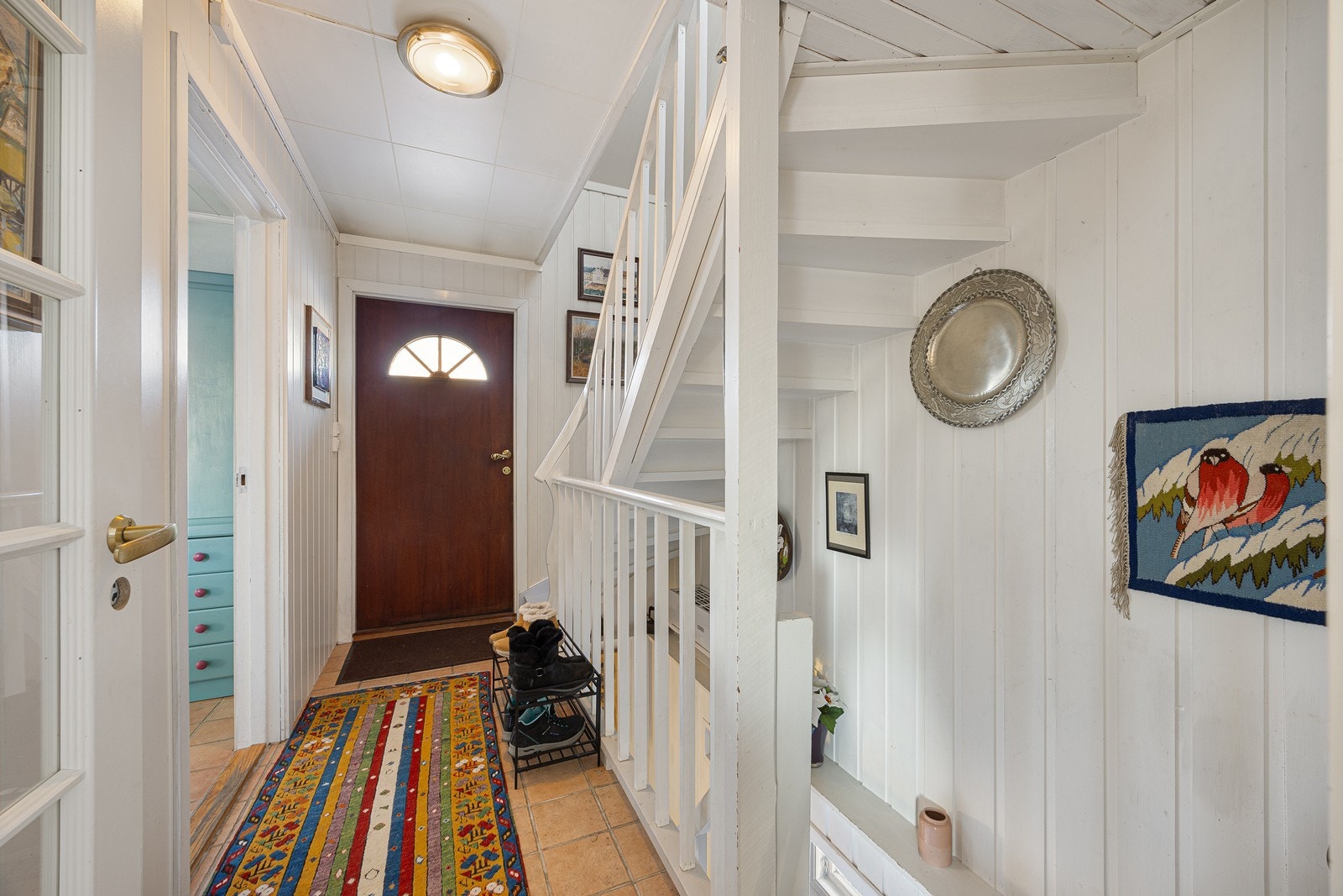 Entréen har lysmalte vegger og sandfargede fliser på gulvet. Galleribilde