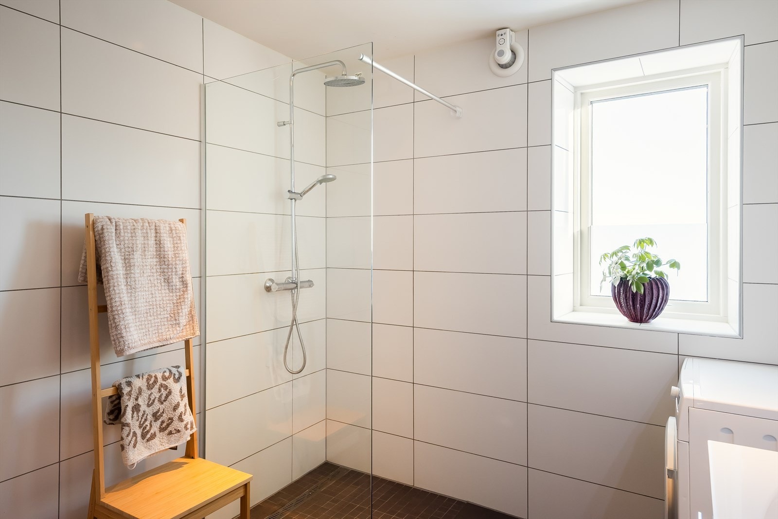 Badet er utstyrt med dusjvegger av glass, vegghengt toalett, innredning med servant og opplegg for vaskemaskin. Vaskemaskin medfølger handelen. Galleribilde