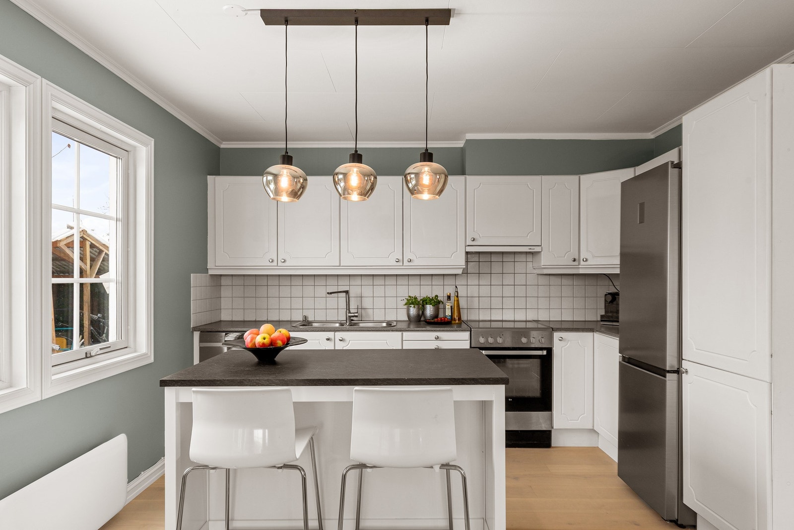 Kjøkkenet er innredet med over-og underskap i lyse profilerte fronter Galleribilde