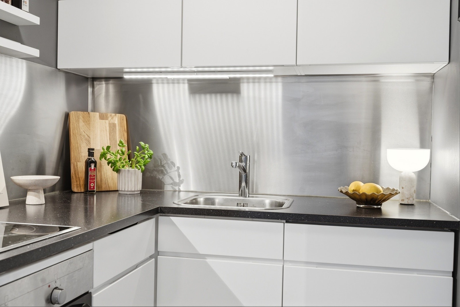 Hvite slette fronter og benkeplate av laminat. Lys under overskap. Galleribilde