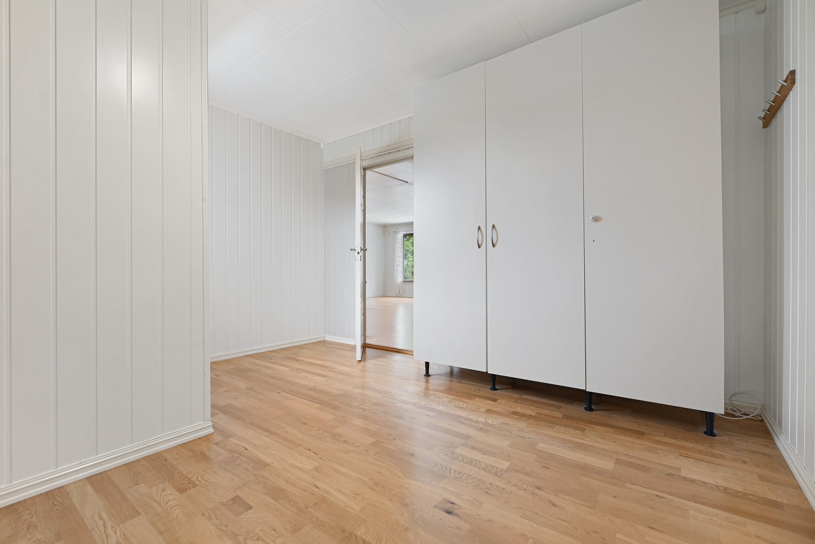 Lyse vegger og gulv, med innebygd skap og dør til tilstøtende rom. Galleribilde