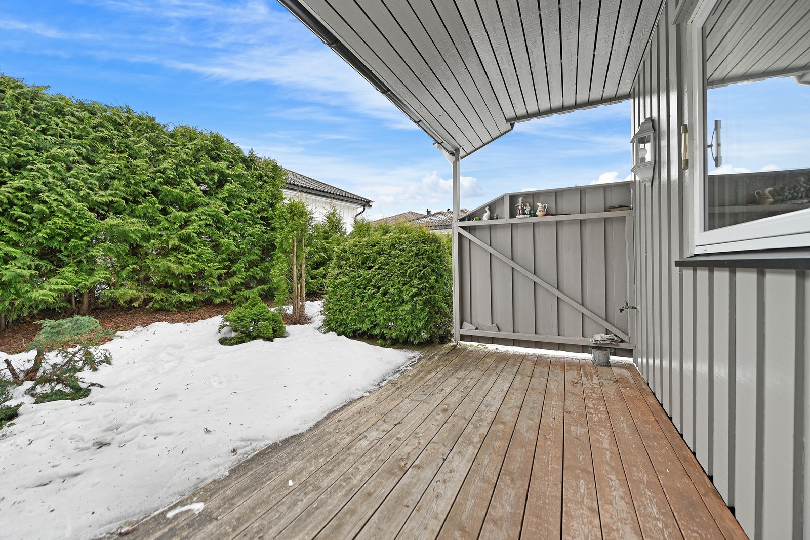 Terrasse med takoverbygg og utsikt mot privat hage. Galleribilde