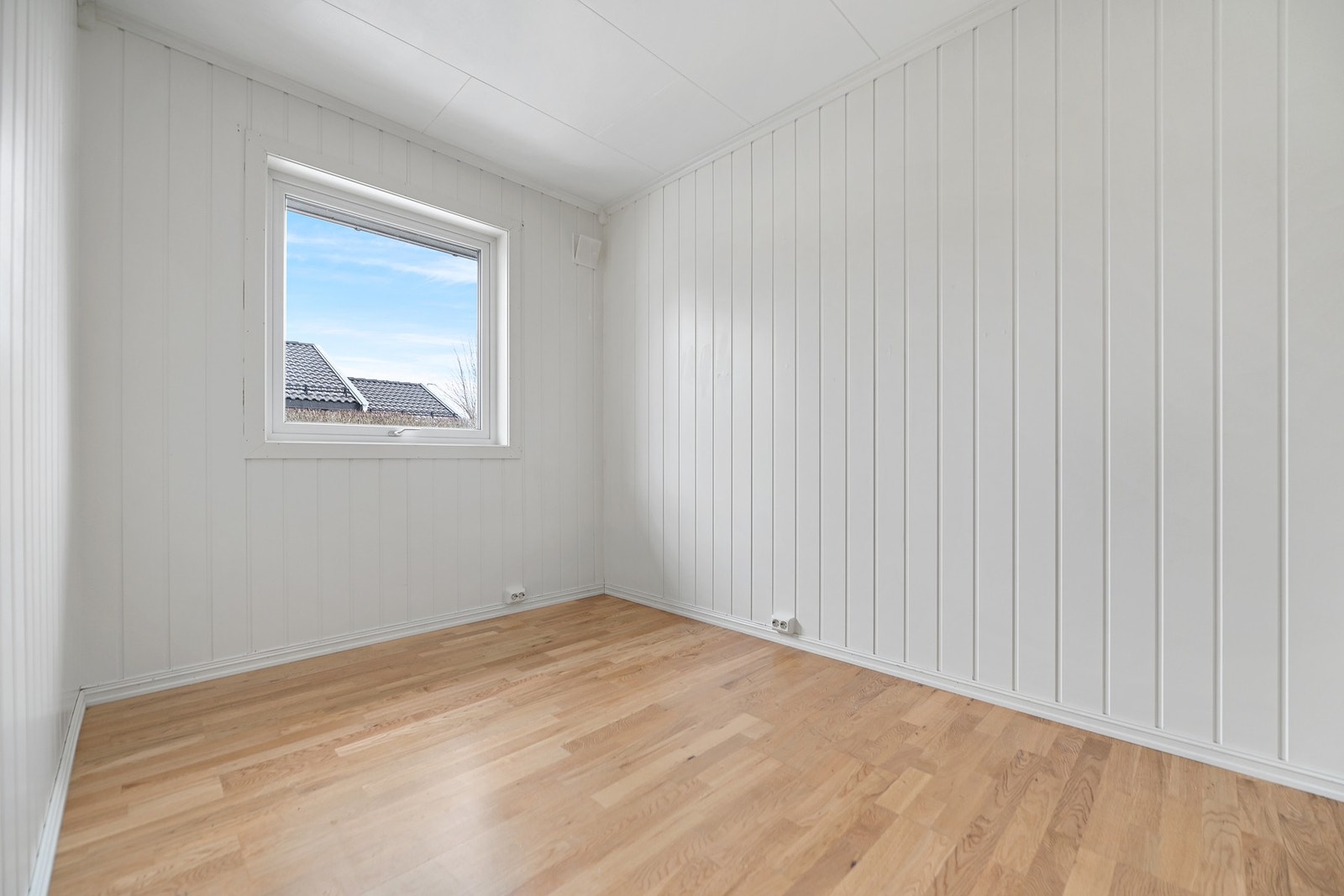 Lyst rom med vindu som gir naturlig lysinnslipp, og vegger med panel. Galleribilde