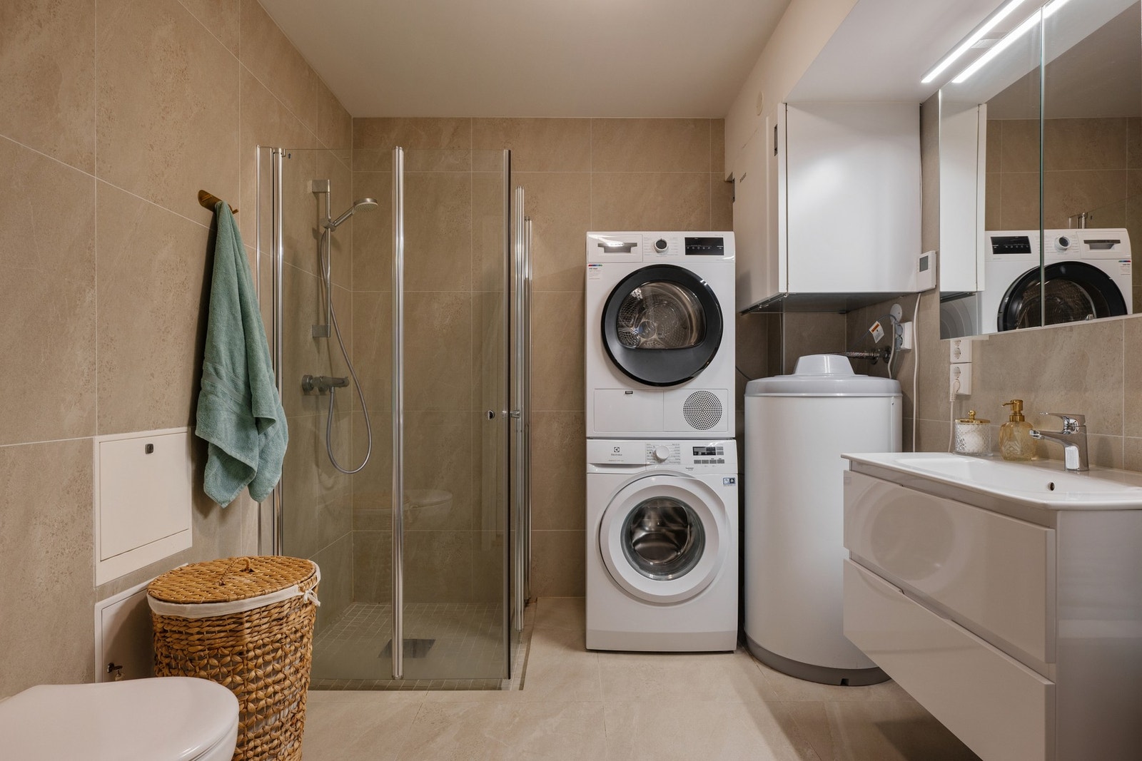 Delikat bad/vaskerom med fliser, gulvvarme og moderne innredning. Galleribilde