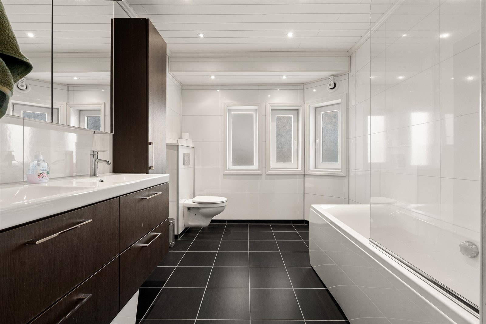 Badet har flislagte gulv med gulvvarme og moderne innredning med speilskap og vegghengt toalett. Galleribilde