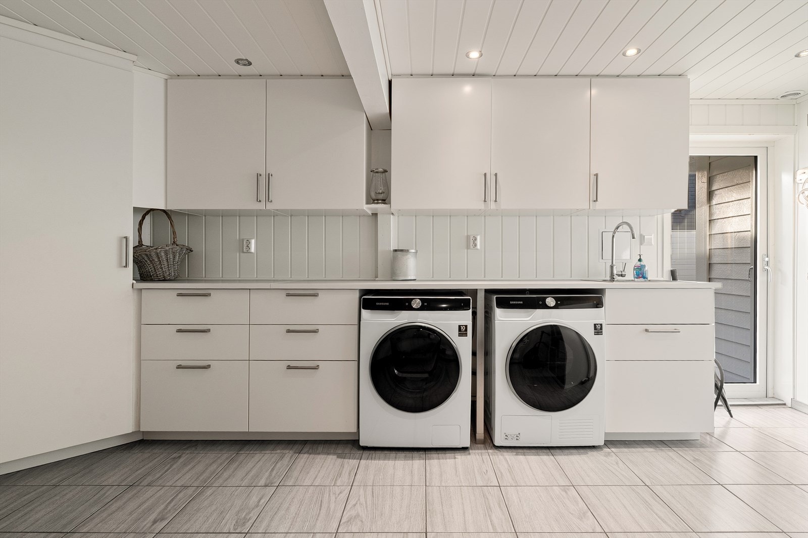 Vaskerommet er innredet med skuffer, skap og laminert benkeplate, med opplegg for vaskemaskin. Galleribilde