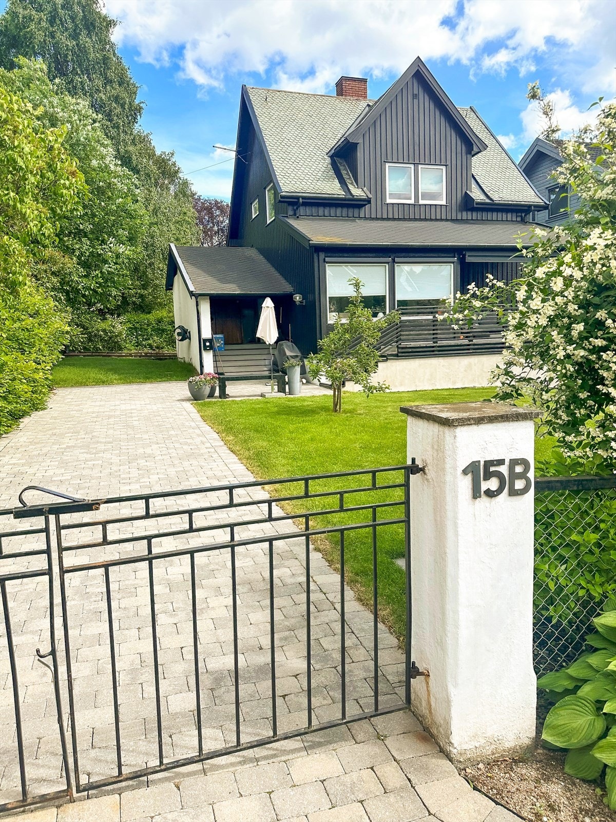 Flat og fin tomt med port mot veien. Opparbeidet uteområde med belegningsstein, plen, tråkkheller, trapp til biloppstillingsplass og beplantning med bl.a. bøkehekk, epletre og hortensia Galleribilde