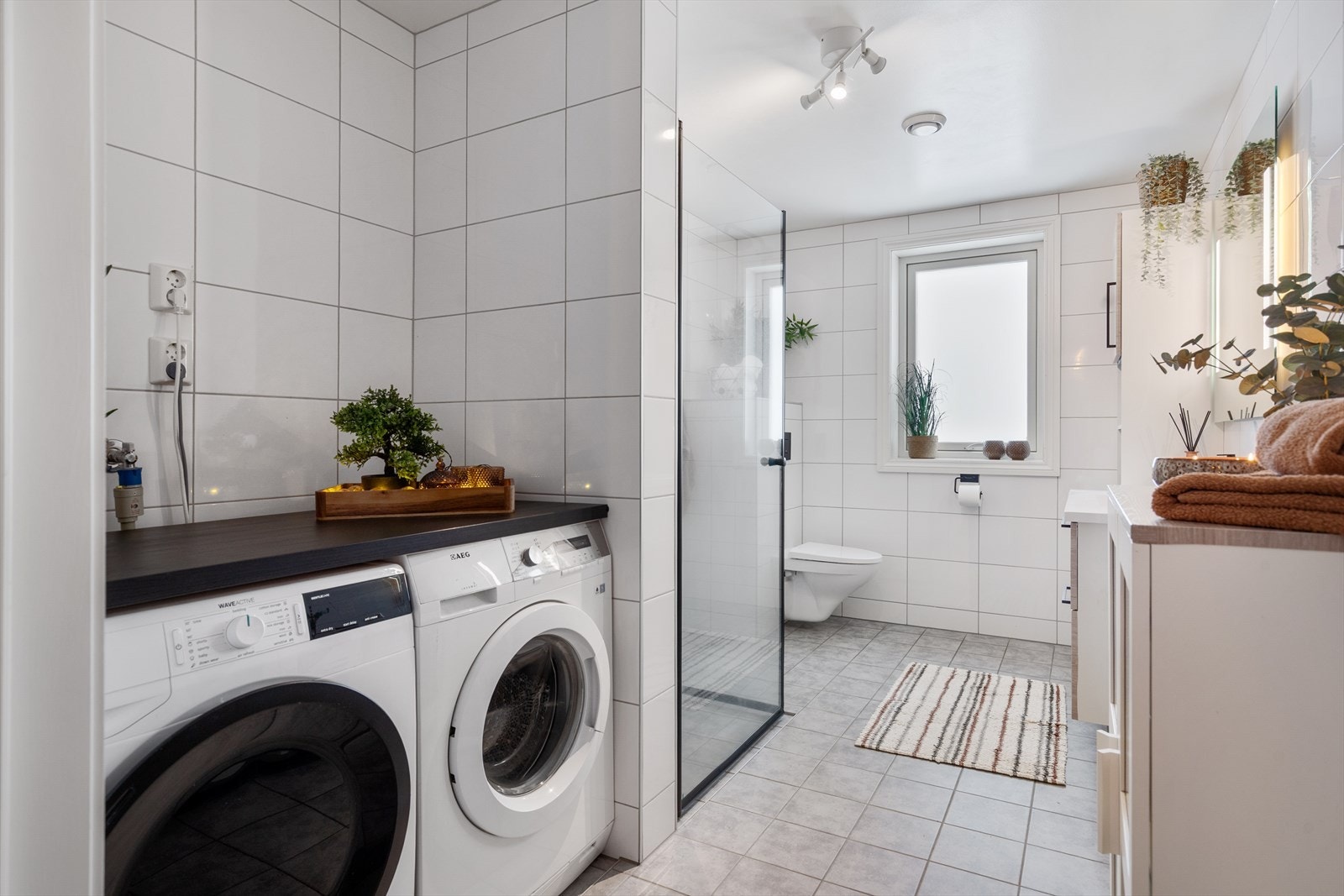 Kombinert bad/vaskerom med egen nisje for vaskemaskin og tørketrommel. Galleribilde