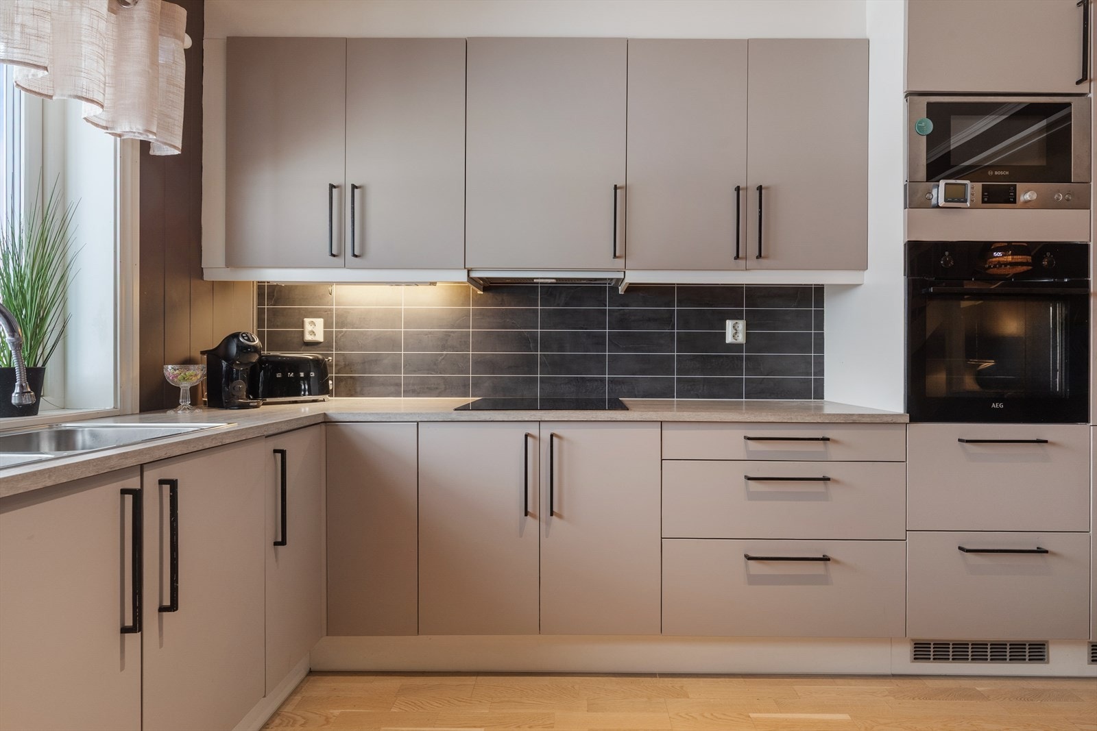 Integrerte hvitevarer bestående av platetopp, stekeovn, mikrobølgeovn, oppvaskmaskin og kombiskap. Galleribilde