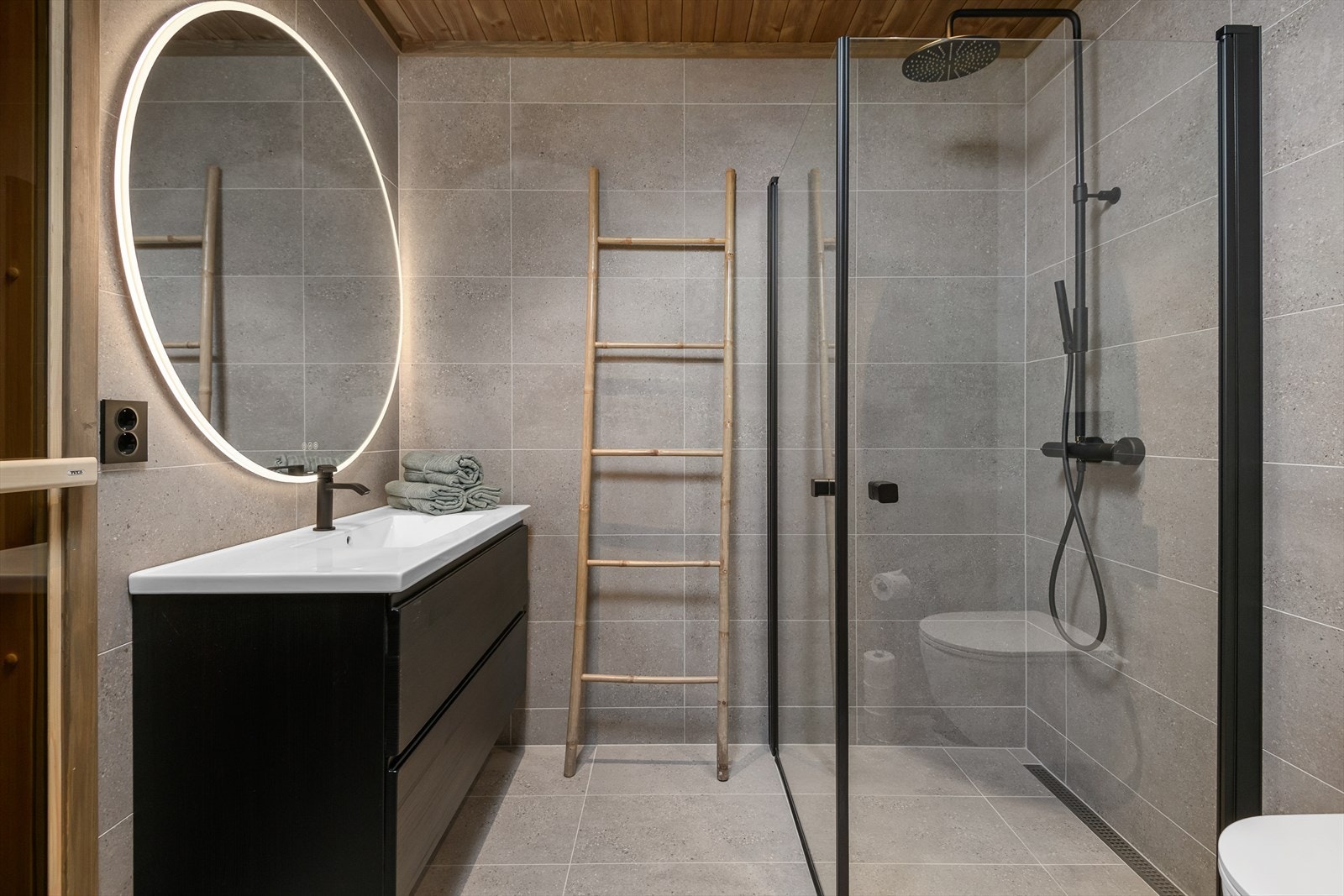 Innbydende hovedbad med lekkert flisvalg, servantinnredning med skuffer for oppbevaring og dusj med glassdører. Vegghengt WC. Galleribilde