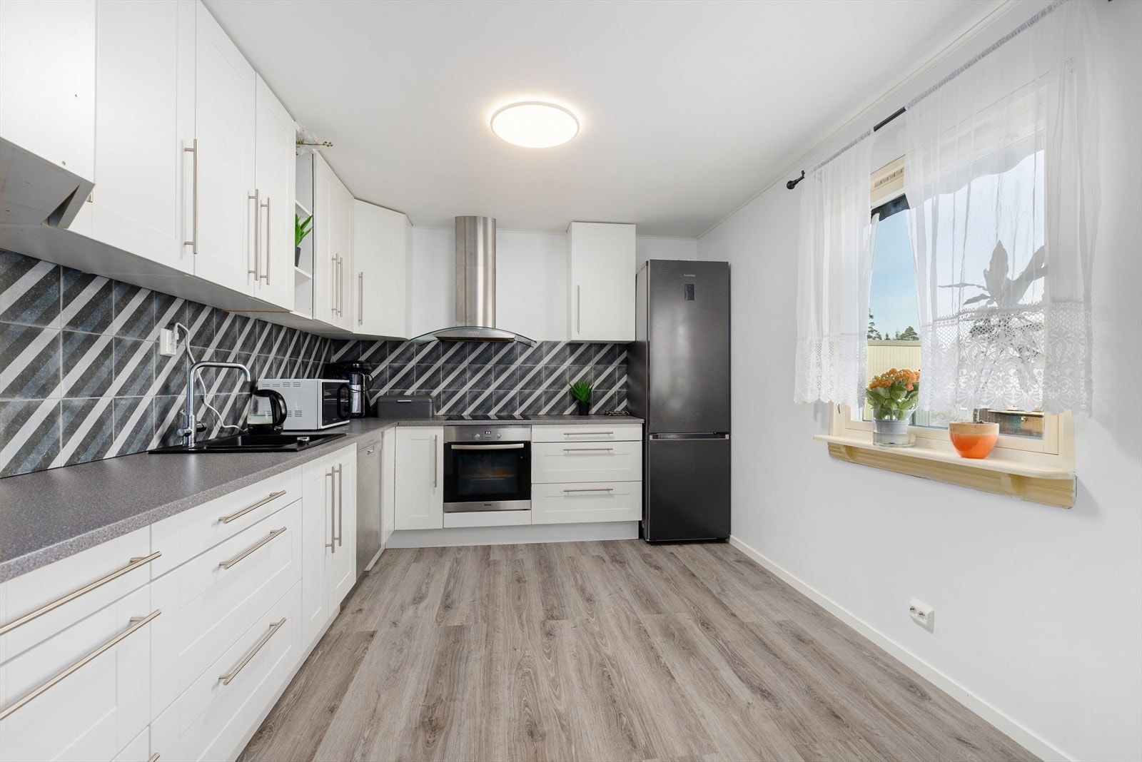 Det pene kjøkkenet har innredning fra 2023 med profilerte fronter som er montert i boligen 2025. Her er det meget god oppbevaringsplass i blant annet takhøye overskap, samt at det er gode arbeidsflater på laminerte benkeplater. Galleribilde