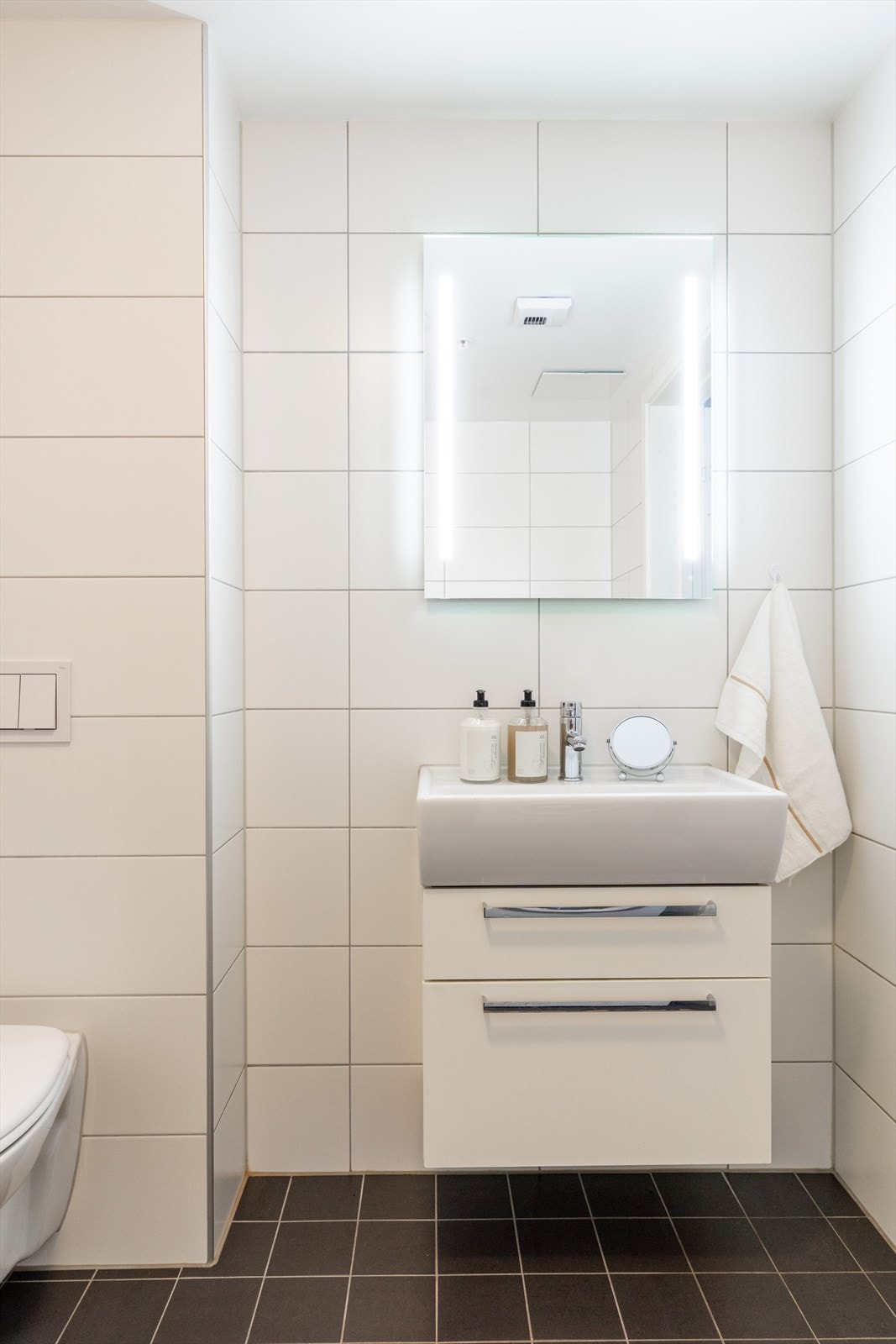 Badet er innredet med vegghengt klosett, baderomsinnredning med heldekkende servant, speil og dusjvegger. Galleribilde