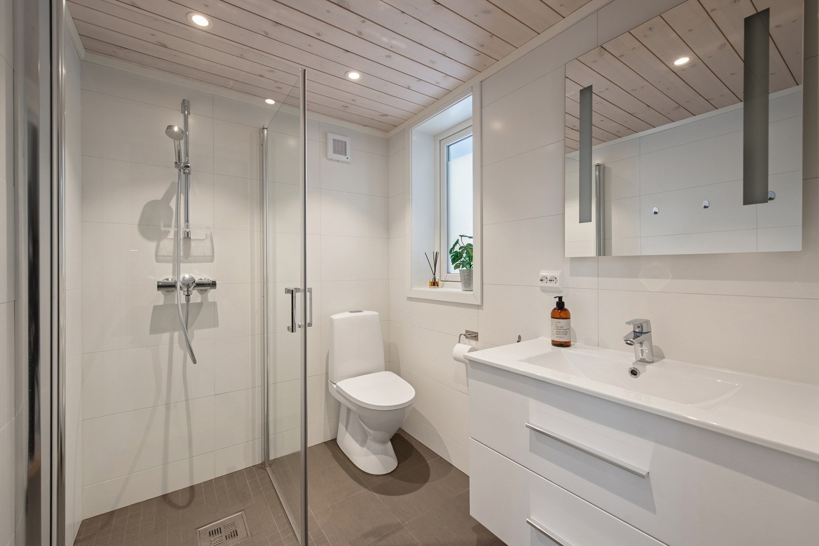 Baderommet er innredet med dusjhjørne med glassvegger, servant med skuffer og downlightbelysning. Galleribilde