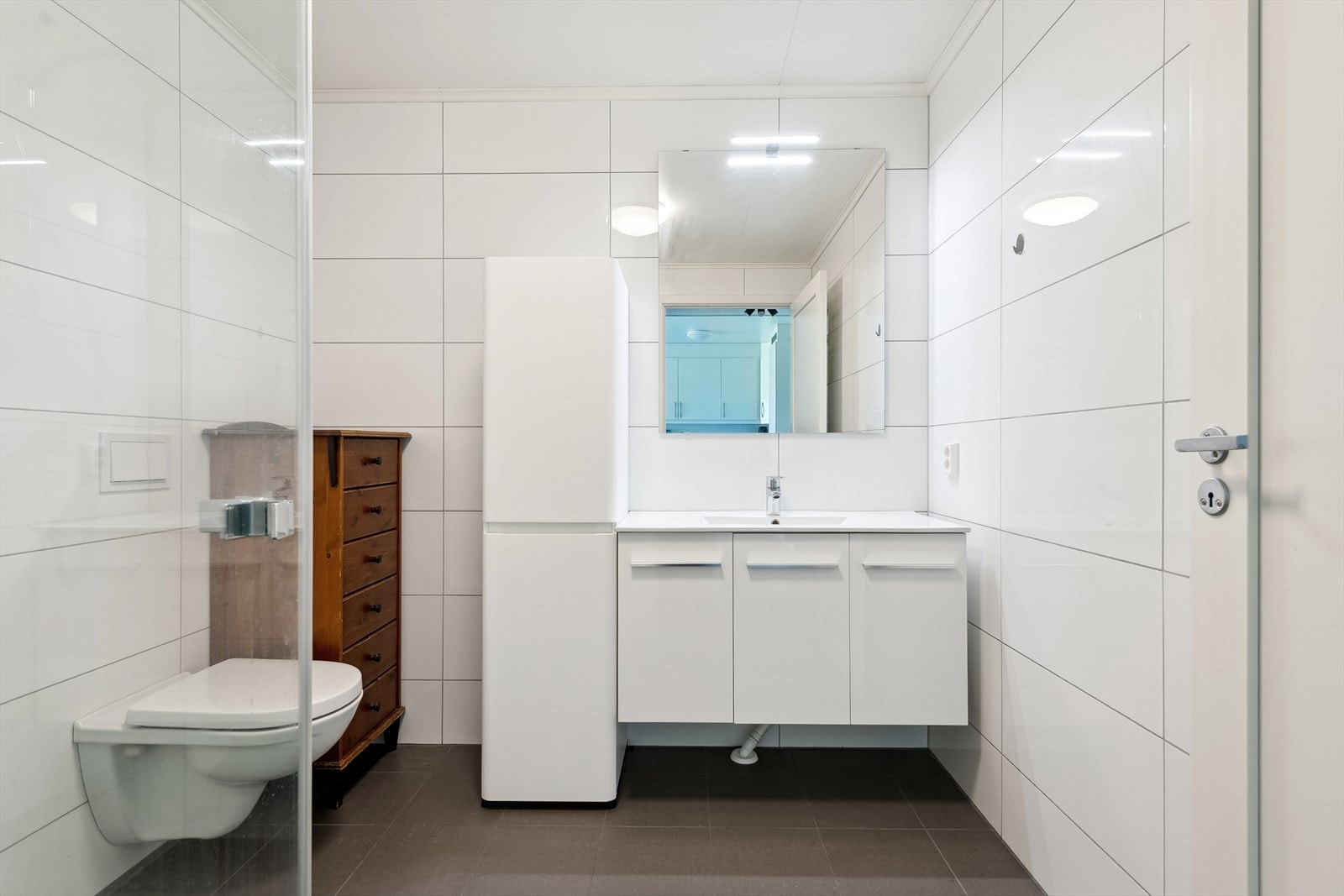 Badet er helfliset og har vannbåren gulvvarme. Innredningen inkluderer servantskap og et praktisk høyskap. Galleribilde