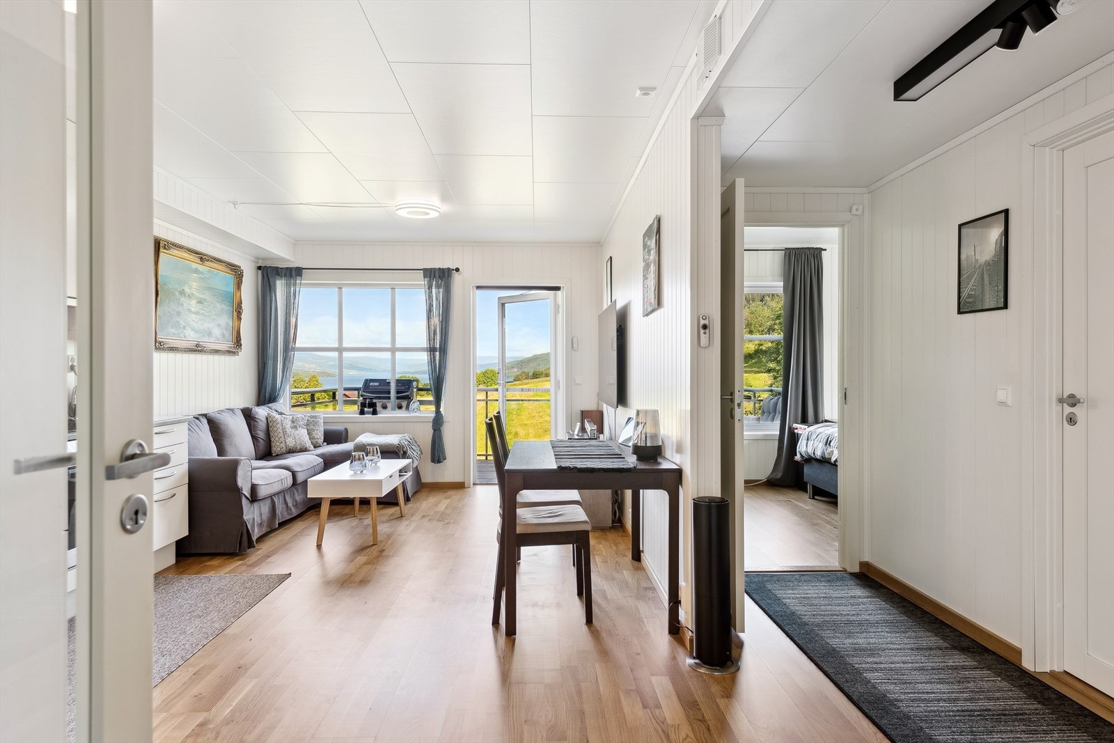 Fra entréen åpner leiligheten seg opp mot en lys og sosial sone med åpen stue- og kjøkkenløsning. Galleribilde