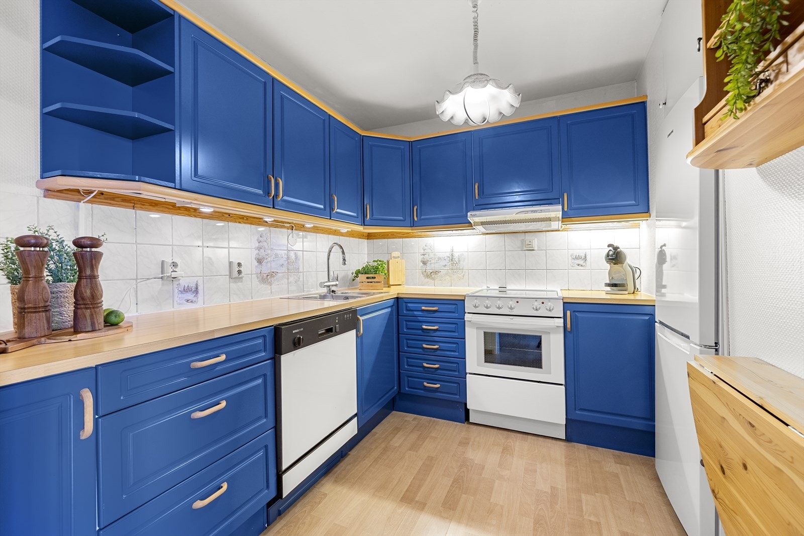 Eldre kjøkkeninnredning med blå, profilerte fronter og lys benkeplate. Galleribilde