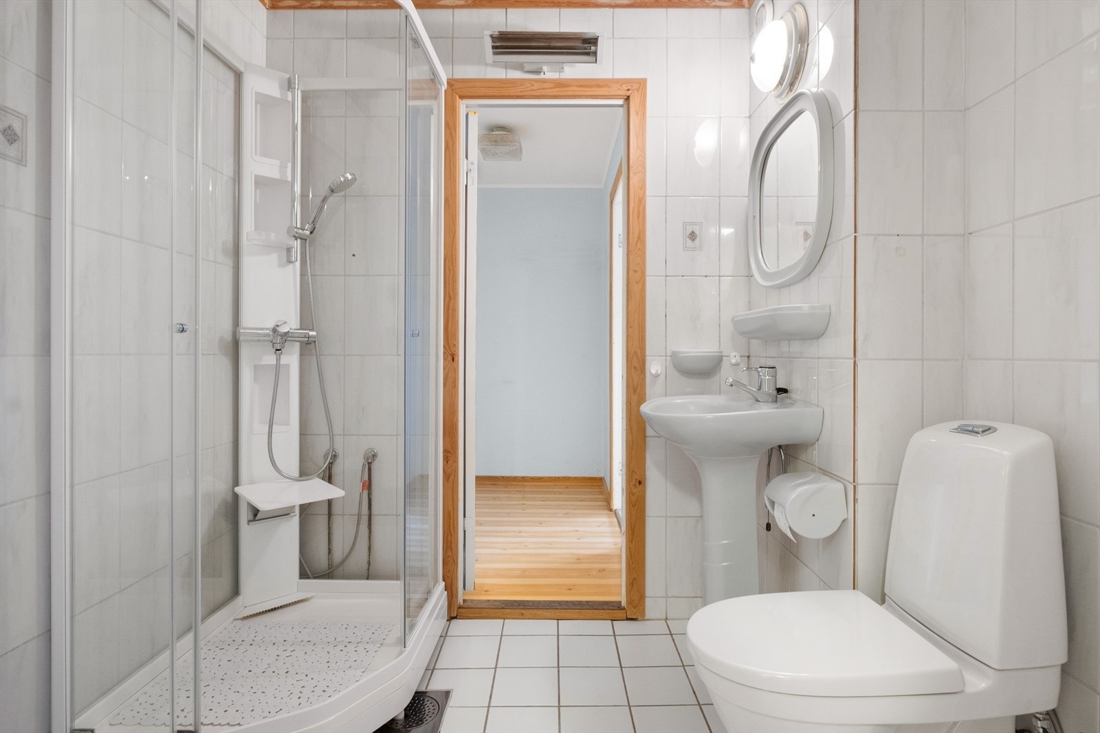 Romslig flislagt baderom med bl.a. dusjhjørne toalett og servant Galleribilde